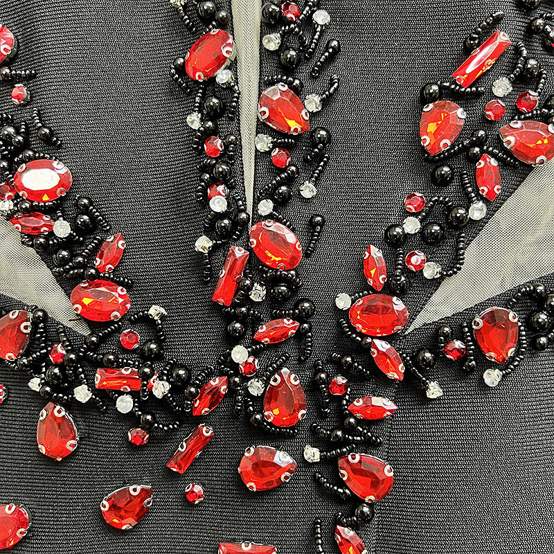 Close-up of a decorative fabric with red and black gemstones on a gray background