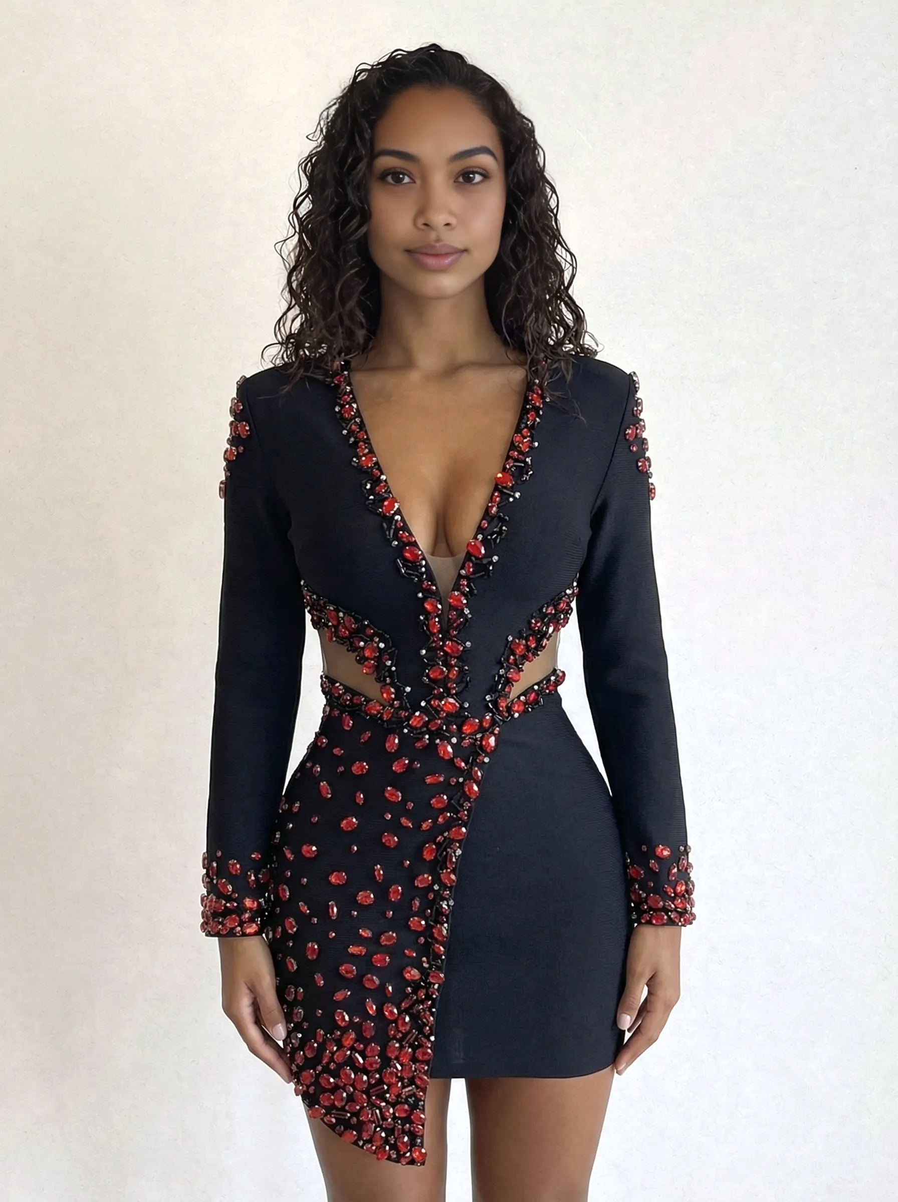 Woman wearing a black dress with red embellishments against a plain background