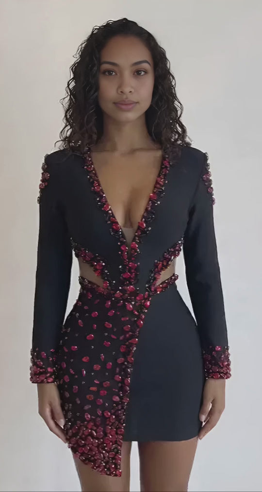 Woman wearing a black dress with red embellishments against a plain background